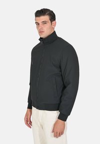 Giubbotto bomber nero in tessuto liscio, con colletto alto, chiusura a zip e tasche laterali. Polsini e orlo a costine per un tocco di texture.
