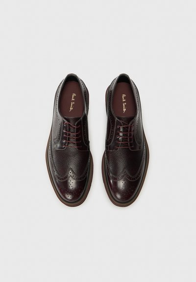 Brogue in pelle bordeaux scuro con superficie testurizzata, design a punta d'ala, perforazioni e chiusura con lacci. Rivestimento interno liscio.