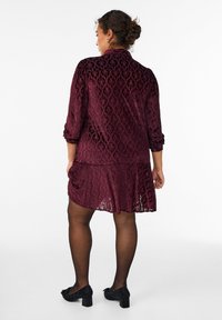 Burgundowa koronkowa sukienka z rozkloszowanym dołem i rękawami o długości trzech czwarte, z teksturowanym wzorem w diamenty i warstwowym wykończeniem dołu.