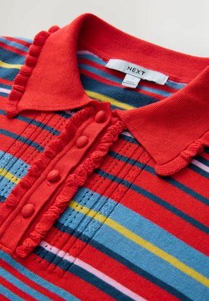 Červené pruhované polo tričko s volánovým golierom a zapínaním. Obsahuje modré, žlté a ružové pruhy, dekoratívne gombíky a textúrovanú tkaninu.