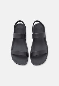 Μαύρα σανδάλια με δύο φαρδιές λουριά και στρογγυλεμένη, υφή στα πέλματα. Κατασκευασμένα από ανθεκτικό υλικό, με απλό και μοντέρνο σχέδιο.