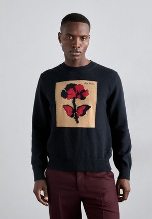 Pulover în navy închis, cu un pătrat central bej și o floare roșie cu accente negre. Manșetele și tivul sunt ribbușate, fabricat dintr-un material moale.