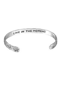 Silver cuff bracelet featuring a textured surface and engraved text reading "LIVE IN THE MOMENT" on the inner band.