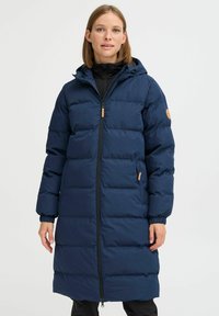 Temno modra puffer jakna z zadrgo spredaj, nastavljivo kapuco, elastičnimi manšetami in stranskimi žepi. Ima horizontalni kviltani vzorec.