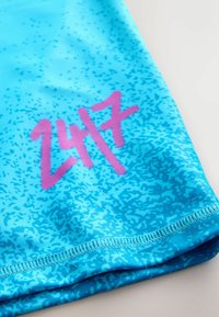 Pantaloncini da bagno con motivo blu realizzati in materiale liscio, caratterizzati da una grafica rosa audace con il numero "247" e orlo cucito lungo il bordo inferiore.