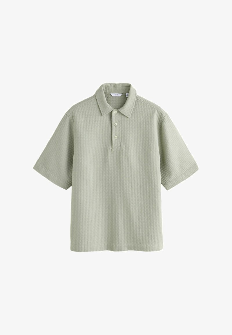 Polo à manches courtes vert clair en tissu texturé avec trois boutons sur la patte de boutonnage, présenté sur fond blanc.