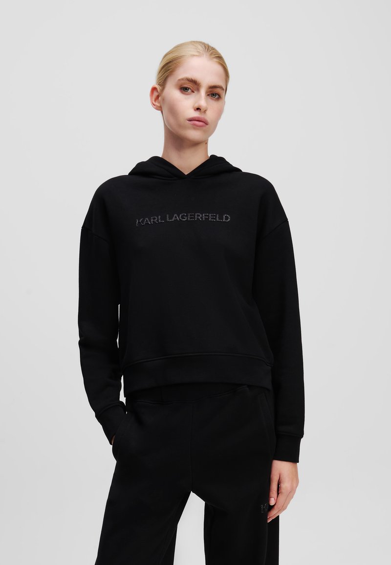 Zwarte hoodie met een gekorte pasvorm, voorzien van geborduurd "KARL LAGERFELD" logo aan de voorkant en geribbelde manchetten en zoom. Glad textuur.