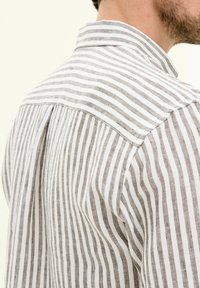 Gestreepte blouse in wit en lichtbruin stof, met een kraag, rugplooi en een gestructureerde linnenweving.