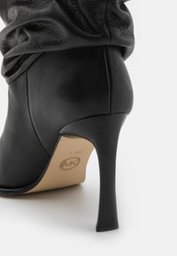 Black leather ankle boot with a high stiletto heel, featuring gathered leather detailing at the top and a smooth texture. Size 7.5M marked inside.