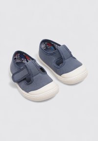 Zapatillas de lona azul marino con suelas de goma blanca, que cuentan con una correa de tipo velcro y un interior estampado con diseños de dibujos animados.