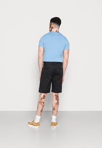 Blue short-sleeve t-shirt, black knee-length shorts, and brown sneakers with white soles. Smooth fabric, straight fit, and minimalist design.
