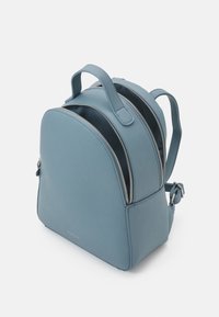Blue faux leather backpack with rounded shape, dual zip compartments, top handle, and adjustable straps. Smooth texture, minimalist design.