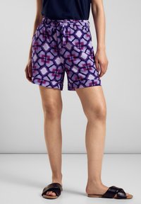 Shorts viola con motivo a rombi, vita elastica e laccetto regolabile. Tessuto leggero e vestibilità comoda. Sandali neri scivolati.