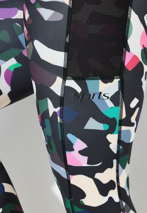Leggings de sport noirs et multicolores avec un motif géométrique, en matériau extensible, avec un panneau en maille et un logo "sports" près de la cuisse.