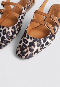 Bailarinas de estampado de leopardo con una parte superior de textil beige y negro, puntera redondeada y dos correas de hebilla de imitación de cuero marrón a través del empeine.
