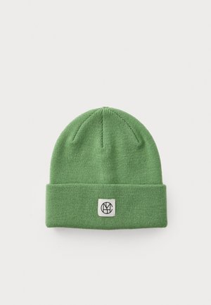 Groene gebreide beanie van zacht materiaal, met een omgeslagen rand en een vierkant patch met een logo. Gelaagd, aansluitend ontwerp.