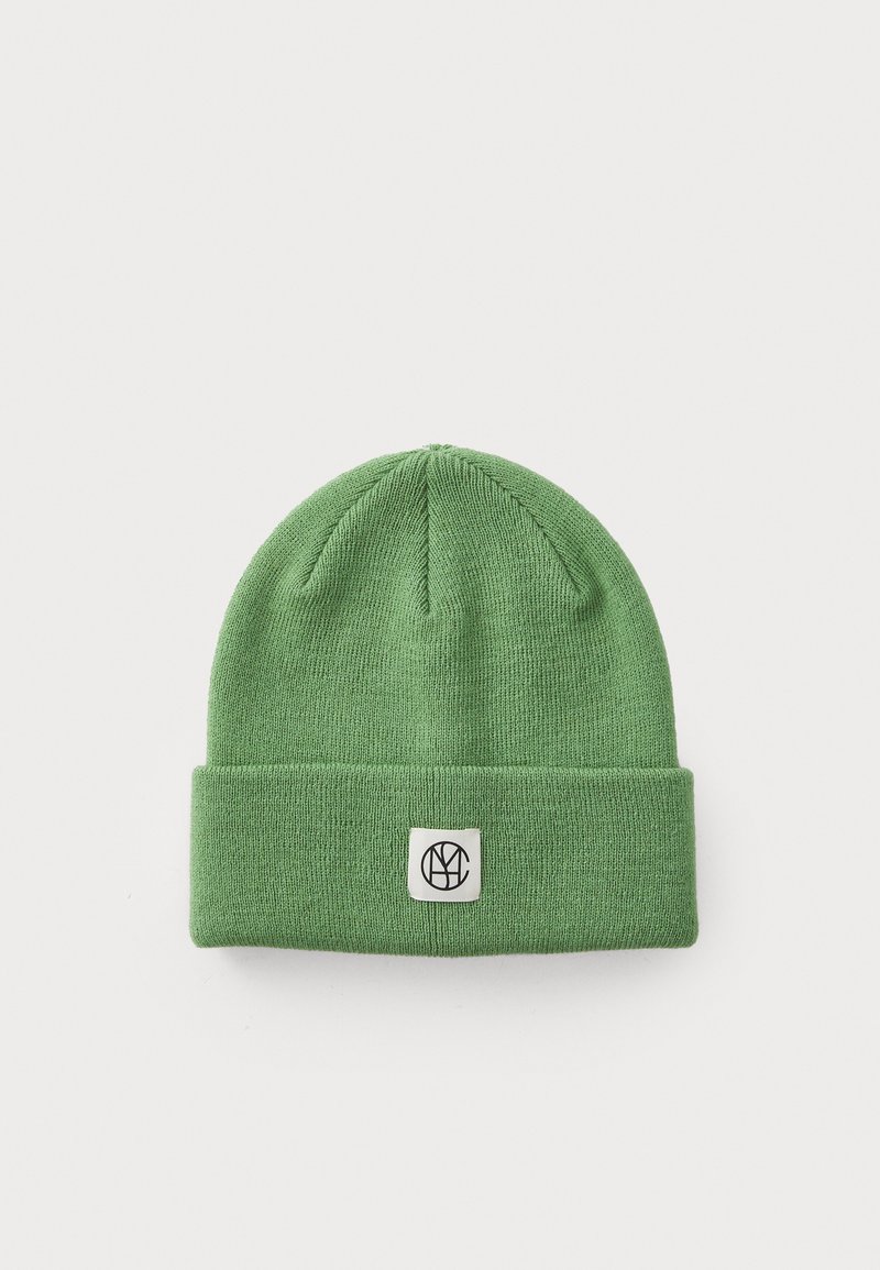Groene gebreide beanie van zacht materiaal, met een omgeslagen rand en een vierkant patch met een logo. Gelaagd, aansluitend ontwerp.