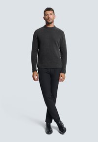Dunkelgrauer Pullover mit rundem Halsausschnitt, kombiniert mit schwarzen, schmal geschnittenen Hosen und schwarzen Ankle-Boots. Der Pullover hat einen weichen, strukturierten Stoff.
