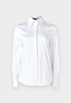 Balta ilga rankovėmis marškiniai, pasiūti iš medvilnės, su smailiu apykakle ir suapvalintu kraštu, turintys lygų paviršių ir be matomų raštų.