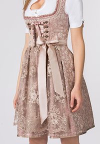 Traditionelles rosa Dirndl aus Seide mit floralem Spitzenmuster, das eine figurbetonte Bluse, ein Satinband zum Binden und einen mehrlagigen Rock mit Spitzenbesatz bietet.