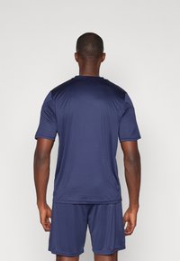 Jersey desportivo e calções em azul-marinho feitos de um tecido leve, com mangas curtas, decote redondo e uma textura suave.