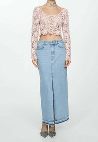 Top corto de encaje rosa claro con patrón floral; falda larga de mezclilla azul claro de talle alto con abertura frontal y dobladillo deshilachado.