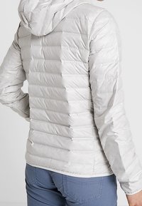 Lekka szara kurtka ocieplana z kapturem, charakteryzująca się poziomym pikowaniem i gładką teksturą. Odpowiednia na codzienne noszenie.