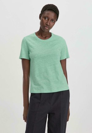 Mintgroene t-shirt met korte mouwen en ronde hals, gemaakt van een gestructureerde, lichte stof. Gecombineerd met donkere broek.