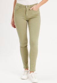 Jean skinny vert olive fabriqué en mélange de coton, avec une fermeture à bouton sur le devant, quatre poches et une texture lisse.
