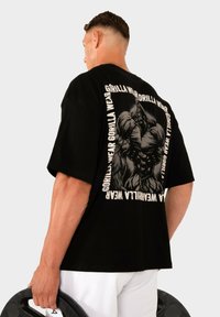 T-shirt en coton noir avec un grand motif d'un gorille musclé dans le dos, entouré de texte "GORILLA WEAR".
