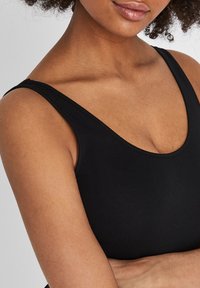 Black, sleeveless top with a scoop neckline. Made of smooth fabric, it features a fitted design and clean stitching along the edges.