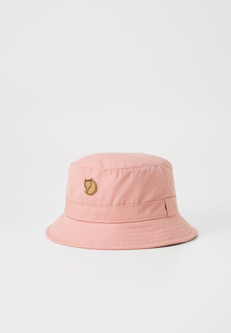 Pink bucket hat made of lightweight fabric with a ribbed texture. Features a gold logo emblem on the front and a wide, floppy brim.