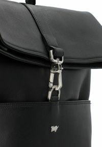 Sac à dos en cuir noir avec une fermeture à rabat magnétique, des garnitures en métal argenté et un petit logo sur la poche avant.