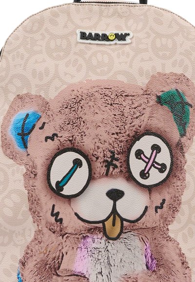 Zaino con grafica di orsacchiotto in peluche rosa, con dettagli ricamati, grandi occhi da cartone e dettagli di cucitura colorati. Sfondo con un motivo leggero.