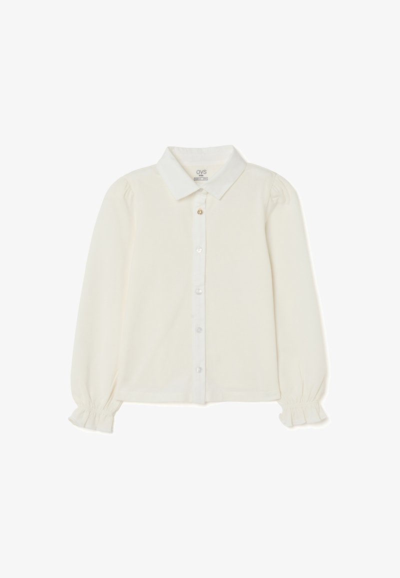 Cream-colored button-up blouse with long sleeves, puffed shoulders, a classic collar, and ruffled cuffs; smooth fabric with a subtle sheen.