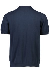 Tumedatest sinise lühikeste varrukatega kudumispolo särgi, millel on ribaga äär ja krae. Sujuv tekstuur, millel on õlgadel peened palmikutega detailid. Tagantvaade.