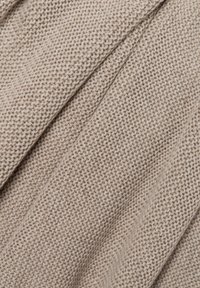 Hellbeige gestrickter Stoff mit einer strukturierten Optik, der eine lockere, weiche Webart aufweist. Keine Verzierungen oder Muster sichtbar.
