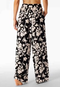 Black floral-patterned wide-leg pants with a soft texture, featuring an elasticated waistband and large white flower designs.
