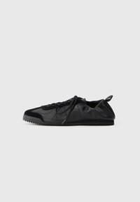 Schwarzer Sneaker mit Obermaterial aus glattem Leder und strukturierten Wildlederakzenten. Verfügt über eine Schnürung, eine runde Zehenform und eine geriffelte Gummisohle.