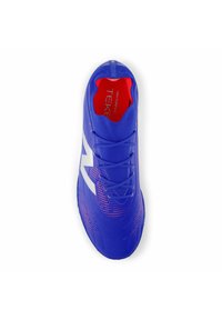 Blue athletic shoe with a textured fabric upper, white accents, and red interior. Features a lace closure and dotted pattern near the sole.