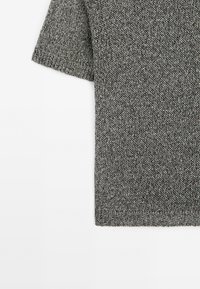 Szara dzianinowa koszulka z krótkim rękawem o fakturowanym wzorze, z zaokrąglonym dekoltem i luźnym krojem.