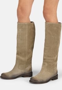 Knöchelhohe, hellbraune Wildlederstiefel mit einem strukturierten Diamantmuster, runder Spitze und niedrigem Holzabsatz, der an der Basis eine abgenutzte Optik aufweist.