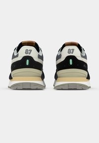 Black and grey sneakers with white and beige accents. Features a textured upper, a padded collar, and reflective detailing on the heel.