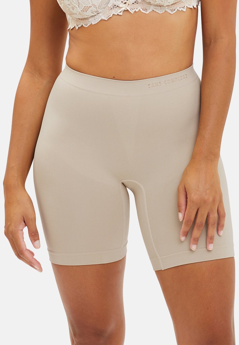 Shorts beige a mitad del muslo hechos de una tela suave y elástica con una cinturilla sin costuras que presenta una sutil textura acanalada y sin costuras visibles.
