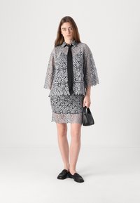 Grau gekleidetes Kleid-Set mit Spitzenbesatz, bestehend aus einem Oberteil mit weitem Ärmel, Kragen und schwarzem Bindegürtel, kombiniert mit einem enganliegenden Spitzenrock.
