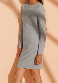 Graues, geripptes, langärmeliges Kleid mit runder Ausschnitt. Figurbetonter Schnitt mit Seitennähten und knielangem Saum. Glatte Textur.