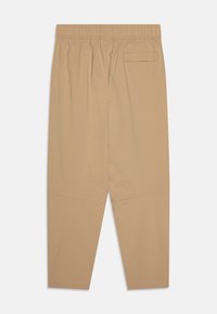 Calças bege de corte relaxado com cintura elástica, um bolso traseiro, pernas retas e detalhes de costura contrastante perto da bainha.