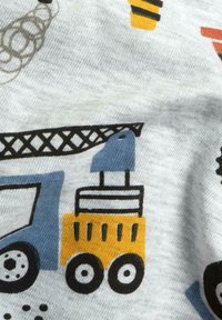 Katoenen stof met een kleurrijke print van voertuigen, waaronder een blauwe vrachtwagen en een gele bouwvoertuig met zwarte wielen en details.