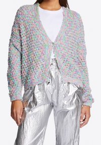 Pastel multi-colored cropped cardigan with textured knit, featuring a single button closure and long sleeves, paired with shiny silver pants.