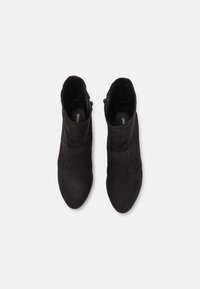 Bottines en daim noir à la forme effilée, fermeture éclair latérale et texture lisse. Design minimaliste avec des détails de surpiqûres subtiles.